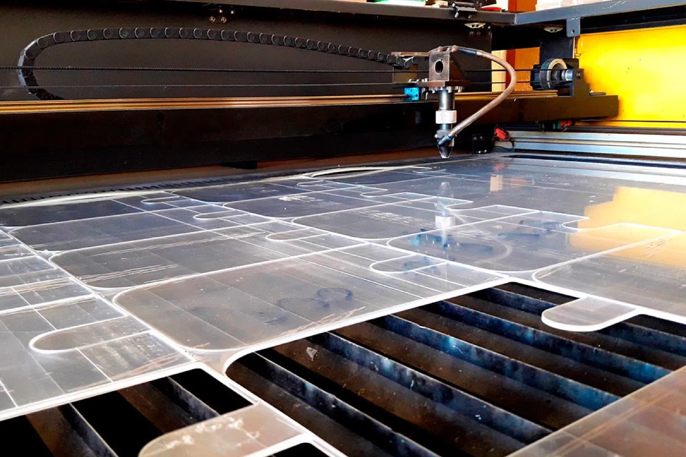 Laser head cutting rounded panels from a clear acrylic sheet