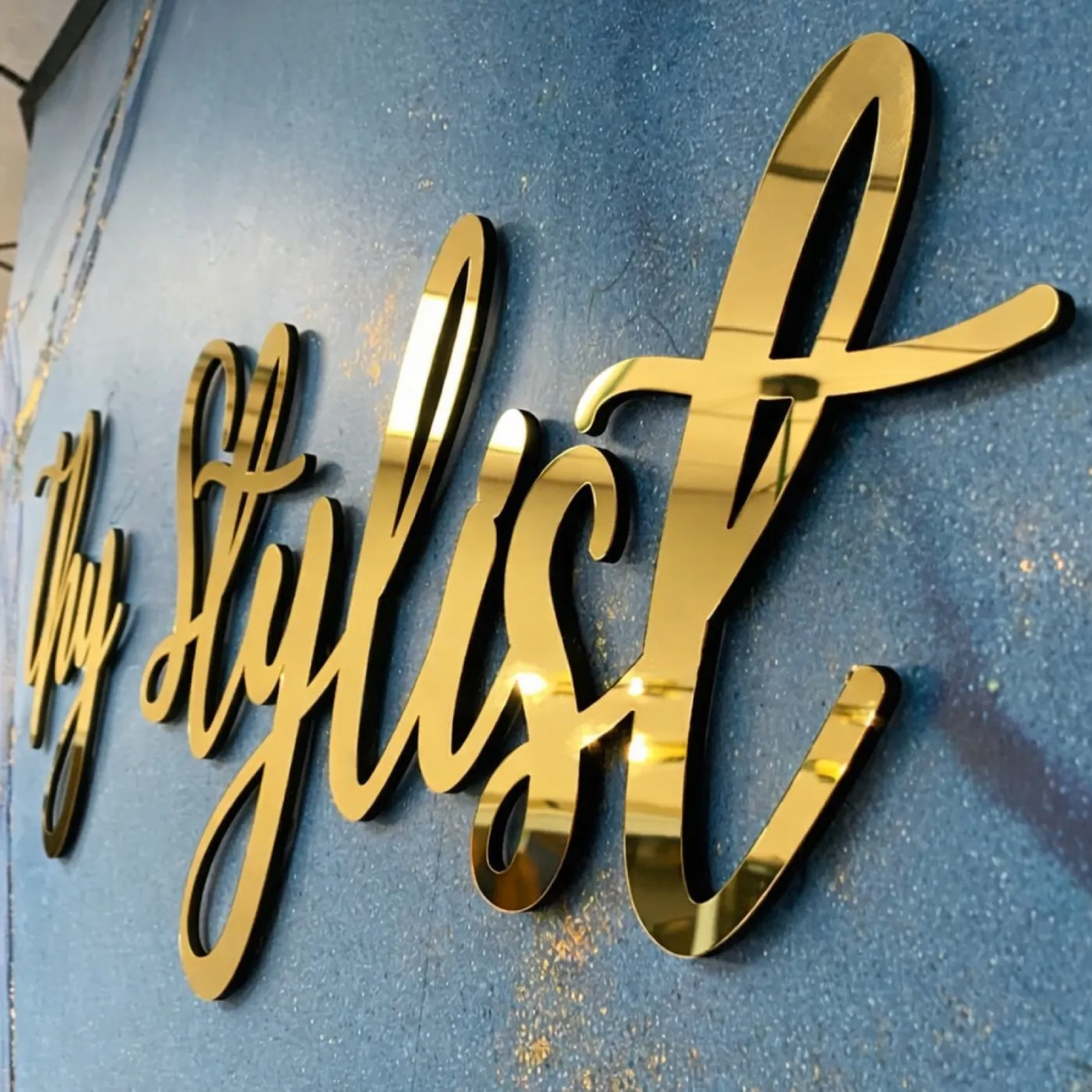 Gold mirror acrylic script lettering mounted on a blue textured wall