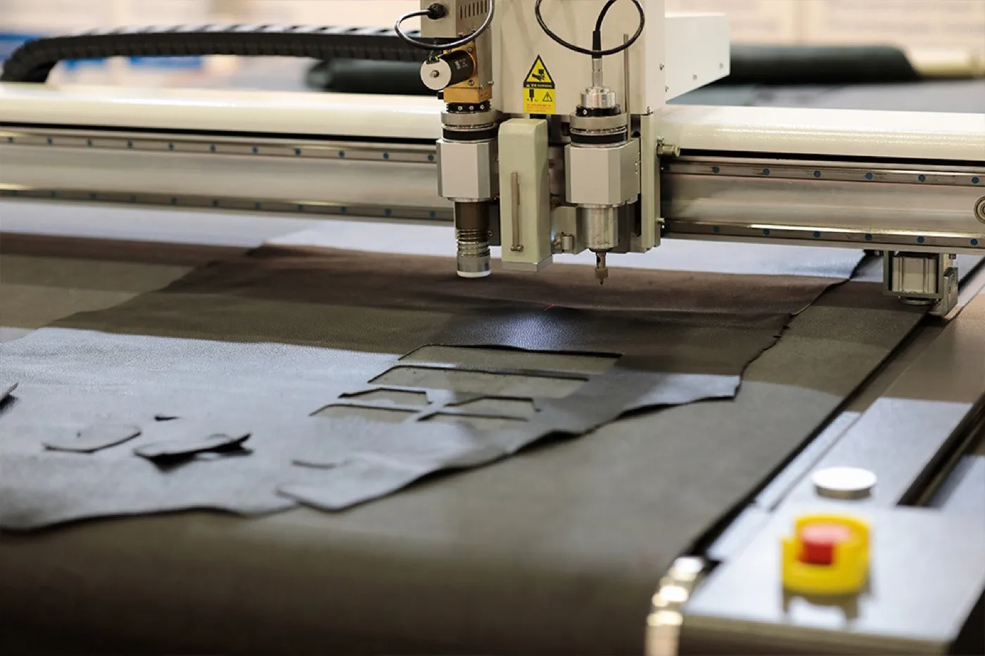 Flatbed digital knife cutter cutting shapes from a black flexible sheet