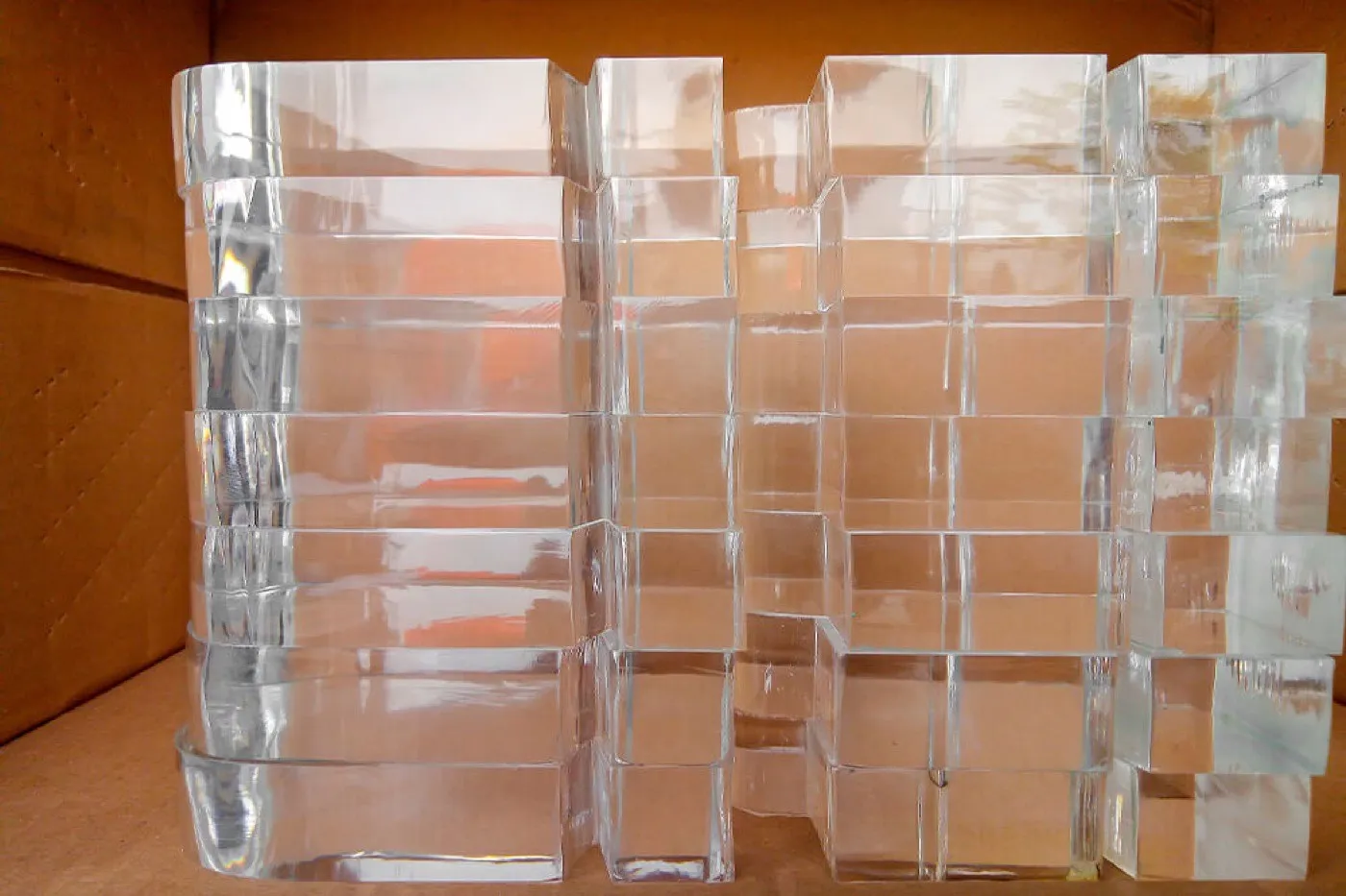 Stacked thick clear acrylic blocks with polished edges packed in a carton